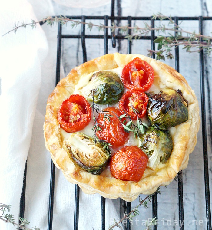This Brussels Sprouts Cherry Tomato Tart is the perfect Christmas appetizer. The round red and green-colored vegetables are like Christmas ornaments nestled on a creamy and cheesy bed with a crispy puff pastry shell! - FiestaFriday.net #appetizer #christmas #tart #cheese #fontina #ricotta #brusselssprouts #cherrytomato